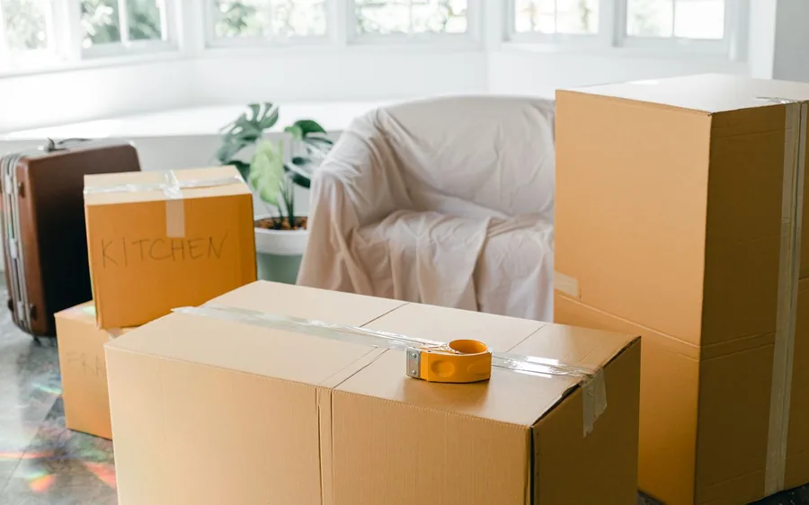 Packed moving boxes labelled Kitchen and Fragile in an empty, sunlit room