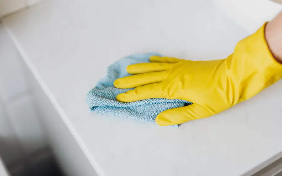 A gloved hand wiping down a clean stone countertop